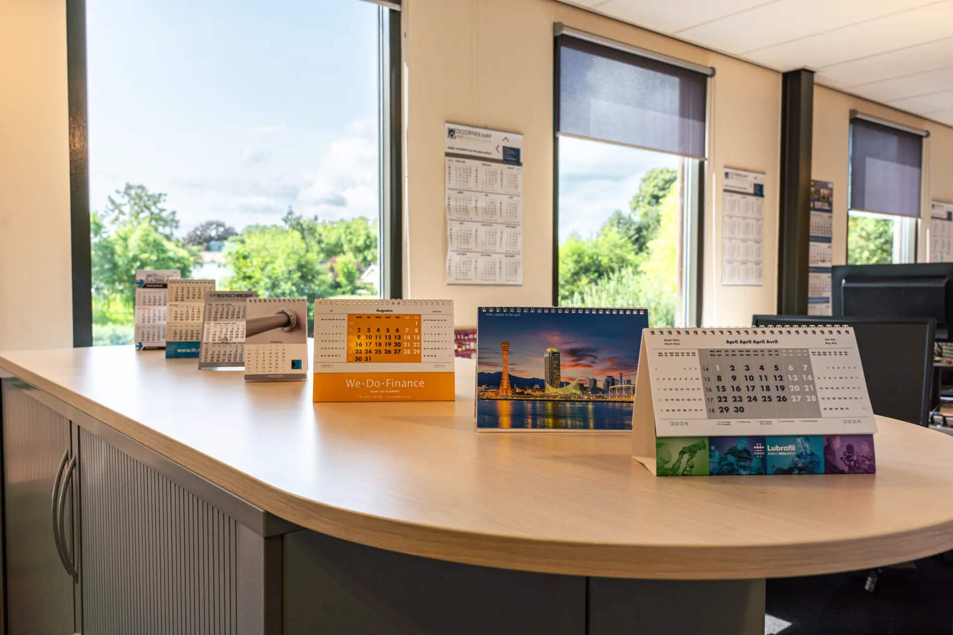 Diverse bureaukalenders op een kast en twee wandkalenders